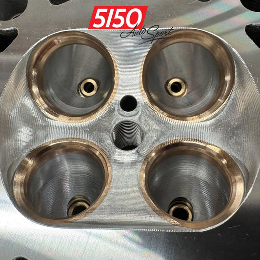 A close-up of a BMW S58 engine cylinder head combustion chamber with upgraded valve seats.